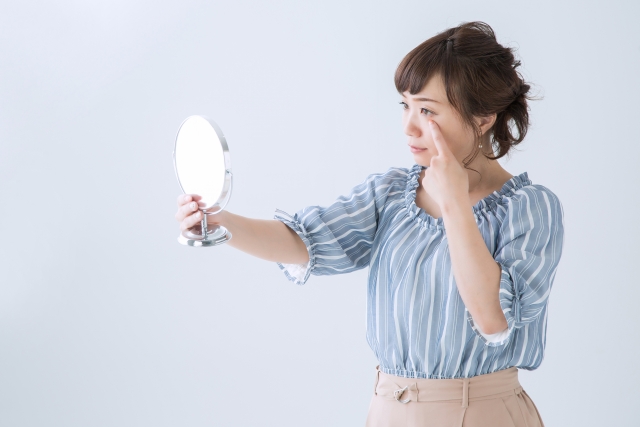 目の下のくまを気にする女性のイメージ写真